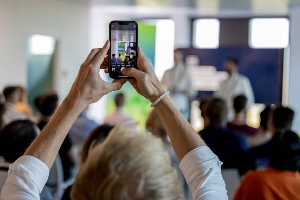 Teilnehmerin filmt einen In&Out Vortrag mit dem Smartphone